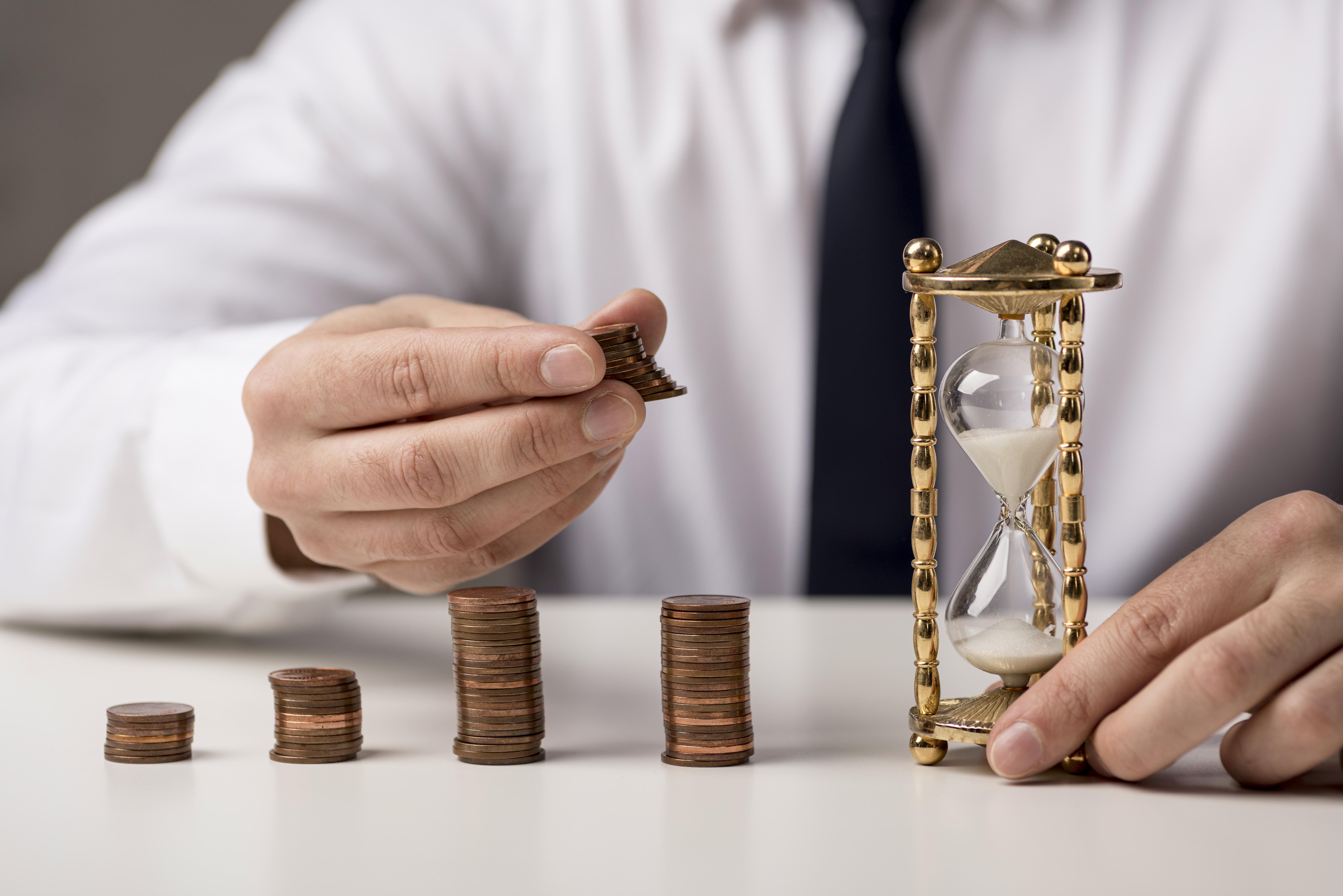 Empresário com ampulheta e moedas representando tempo e economia